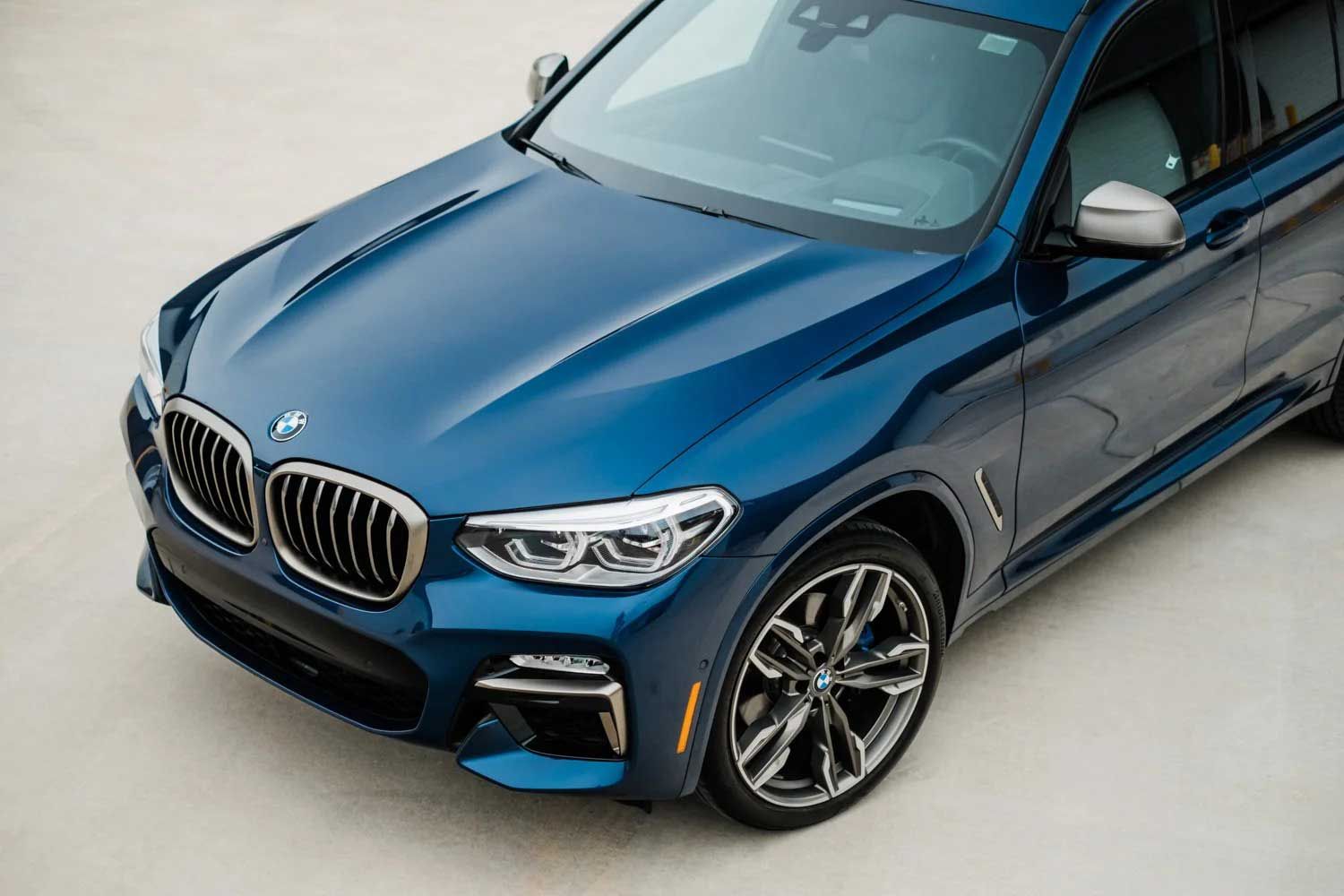 Blue BMW X3 SUV with chrome grill, parked on concrete.