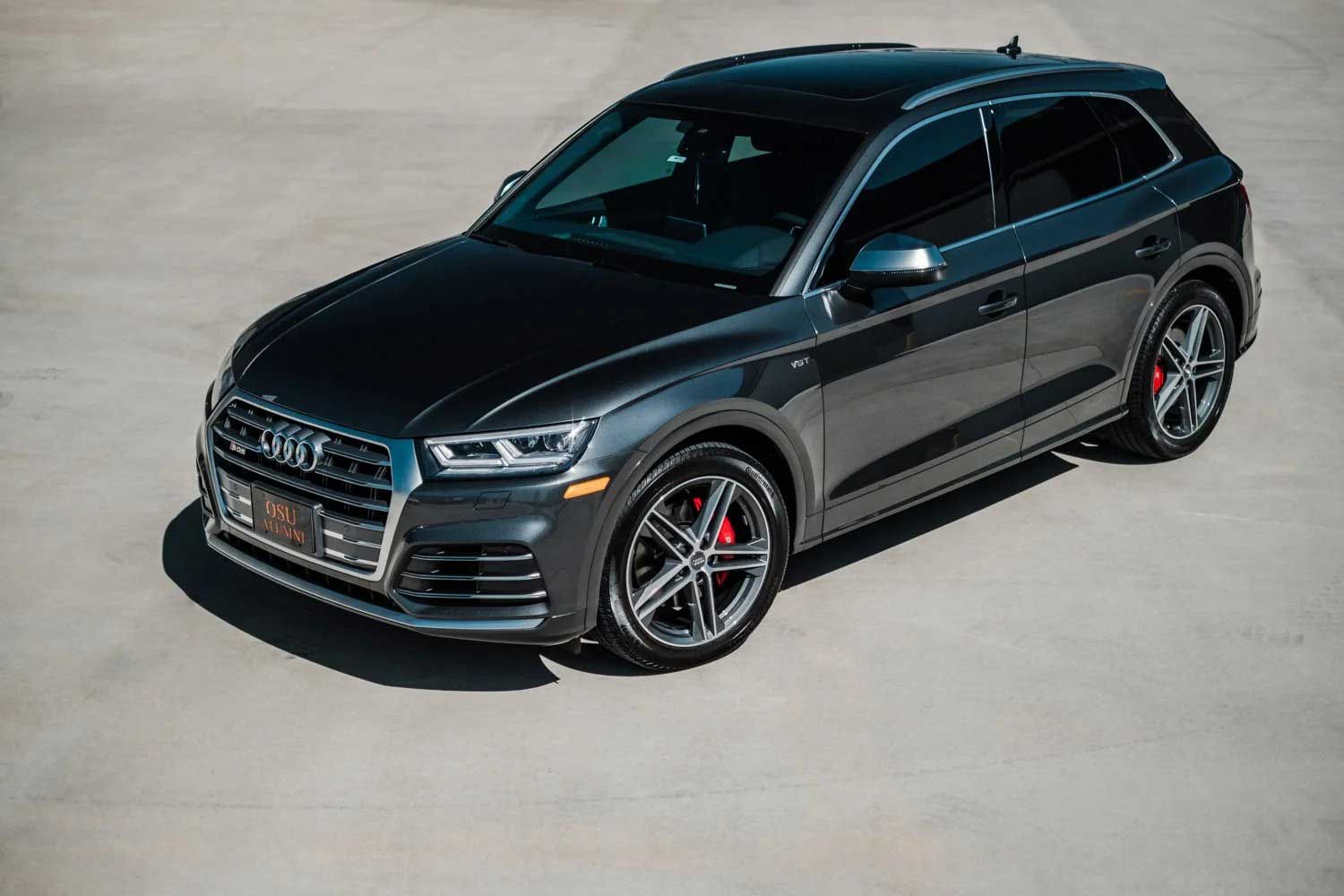 Dark gray Audi SUV on a concrete surface. Red brake calipers visible.