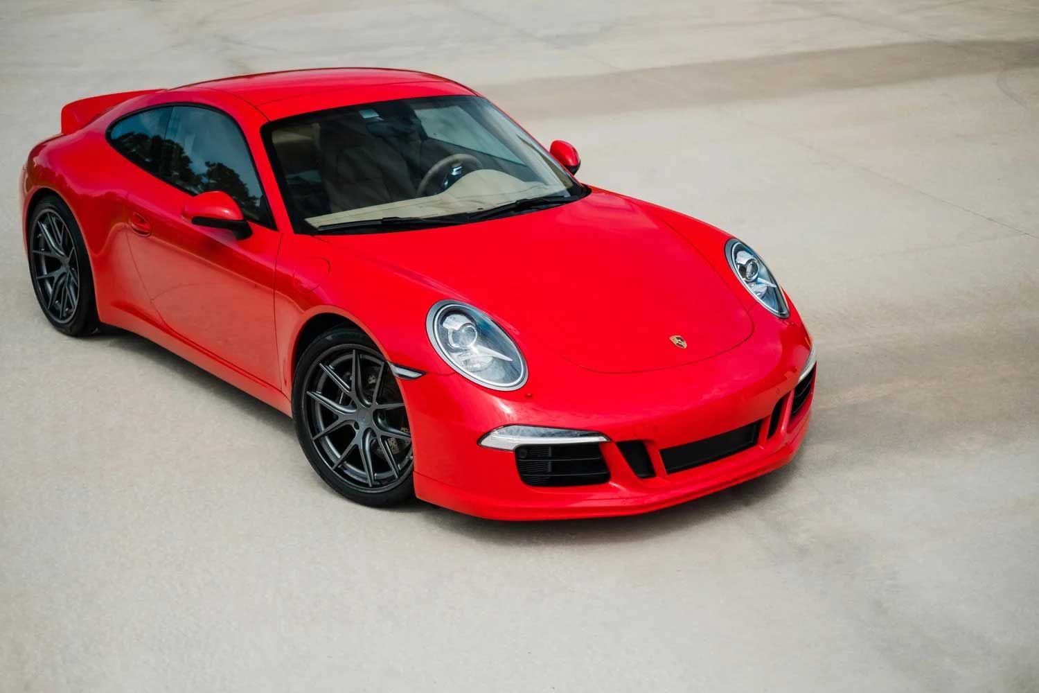 Red Porsche sports car on a light-colored surface, angled view.