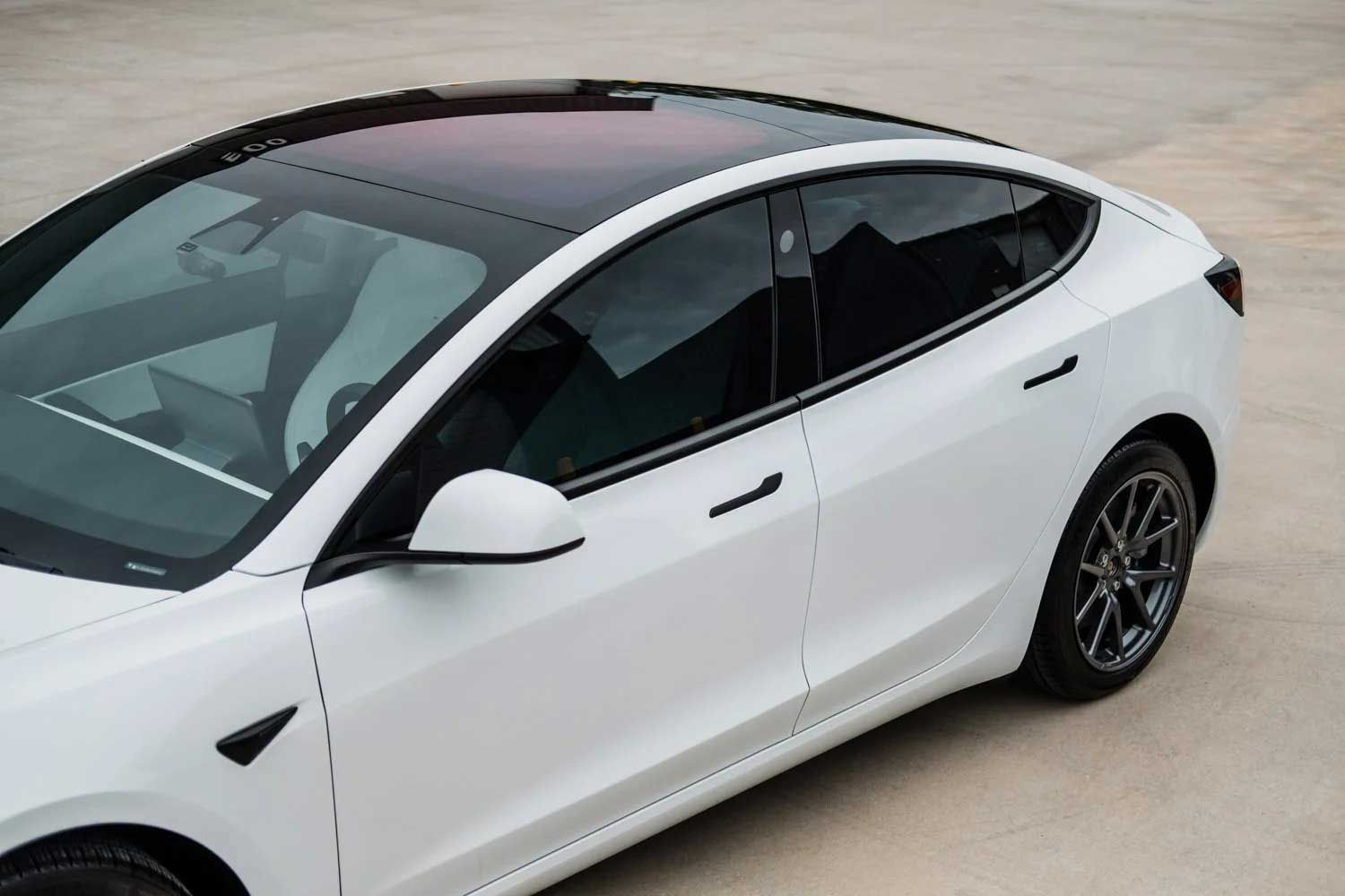 White Tesla Model 3 with a black roof parked on concrete.