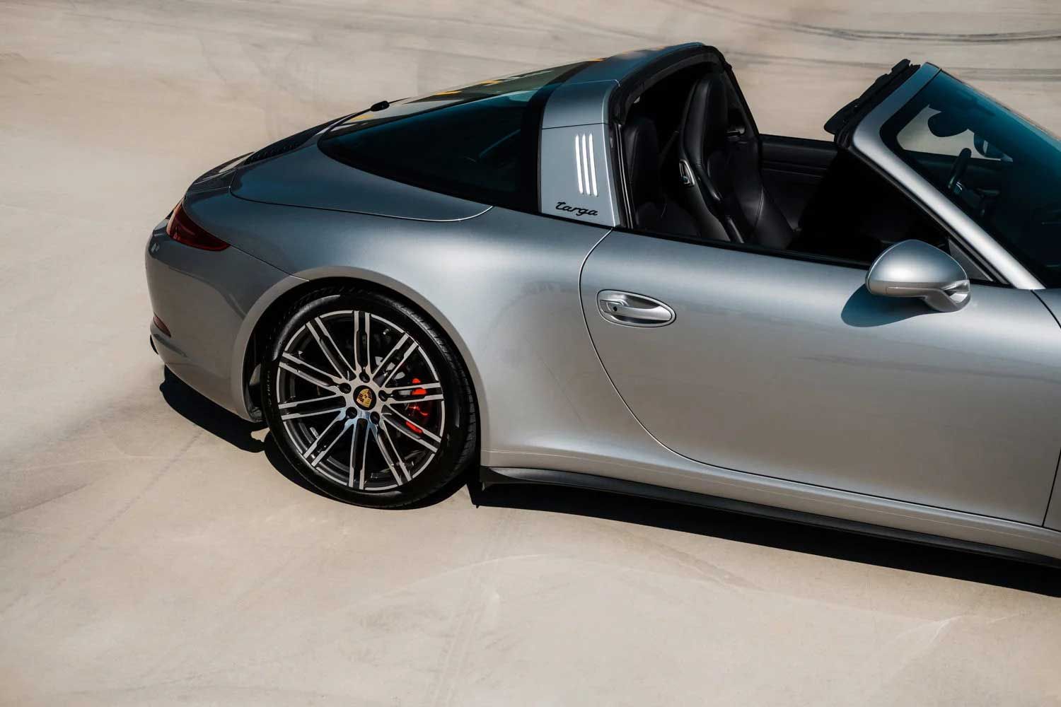 Silver Porsche 911 Targa parked on a light-colored surface with black seats and a black roof.