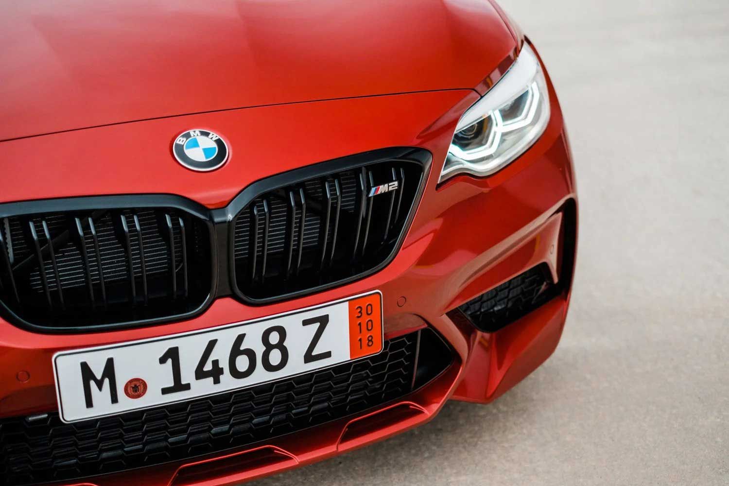 Red BMW M2 car front with black grill, license plate, and headlights.