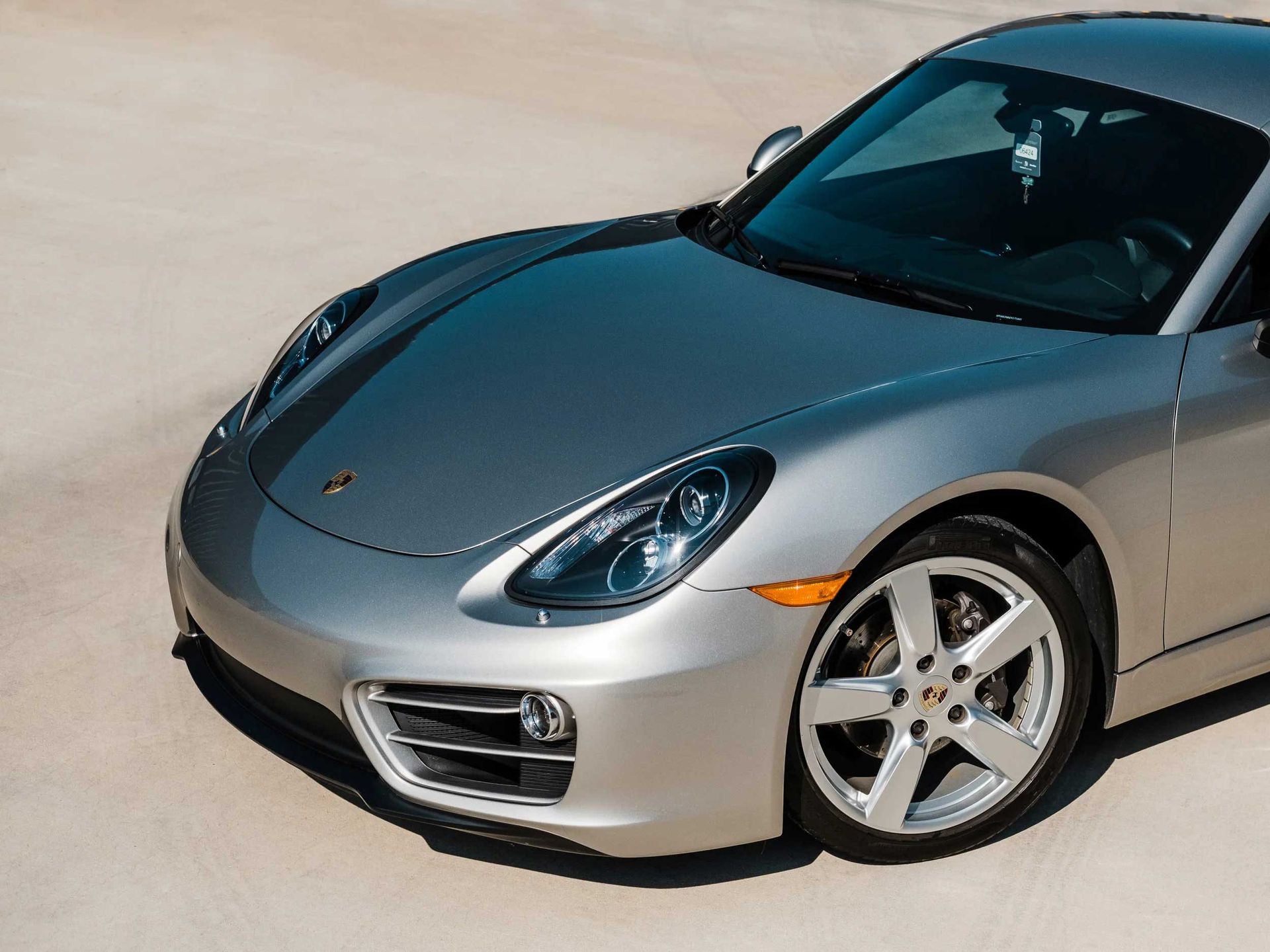 Silver Porsche sports car parked on a light-colored surface; front quarter view.