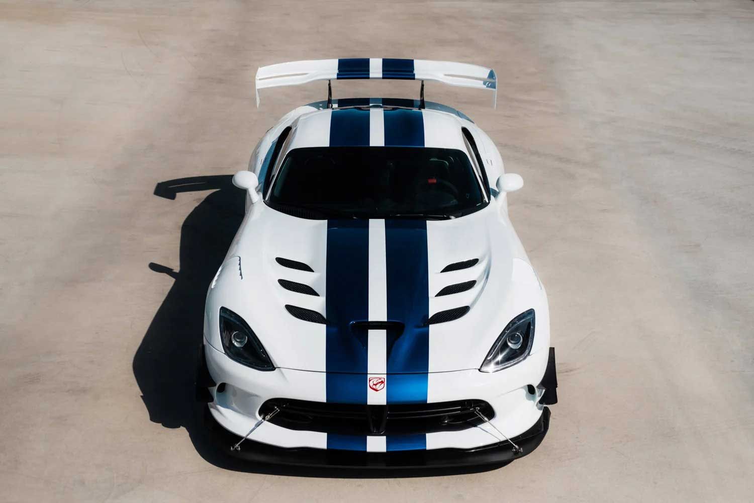 White Dodge Viper race car with blue stripes, viewed from above, on a concrete surface.
