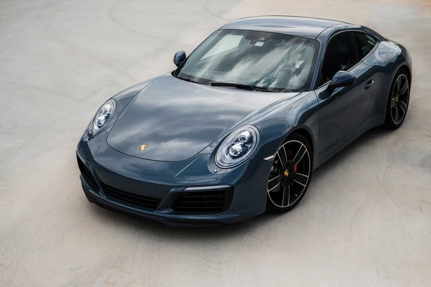 Blue Porsche sports car parked on a concrete surface.