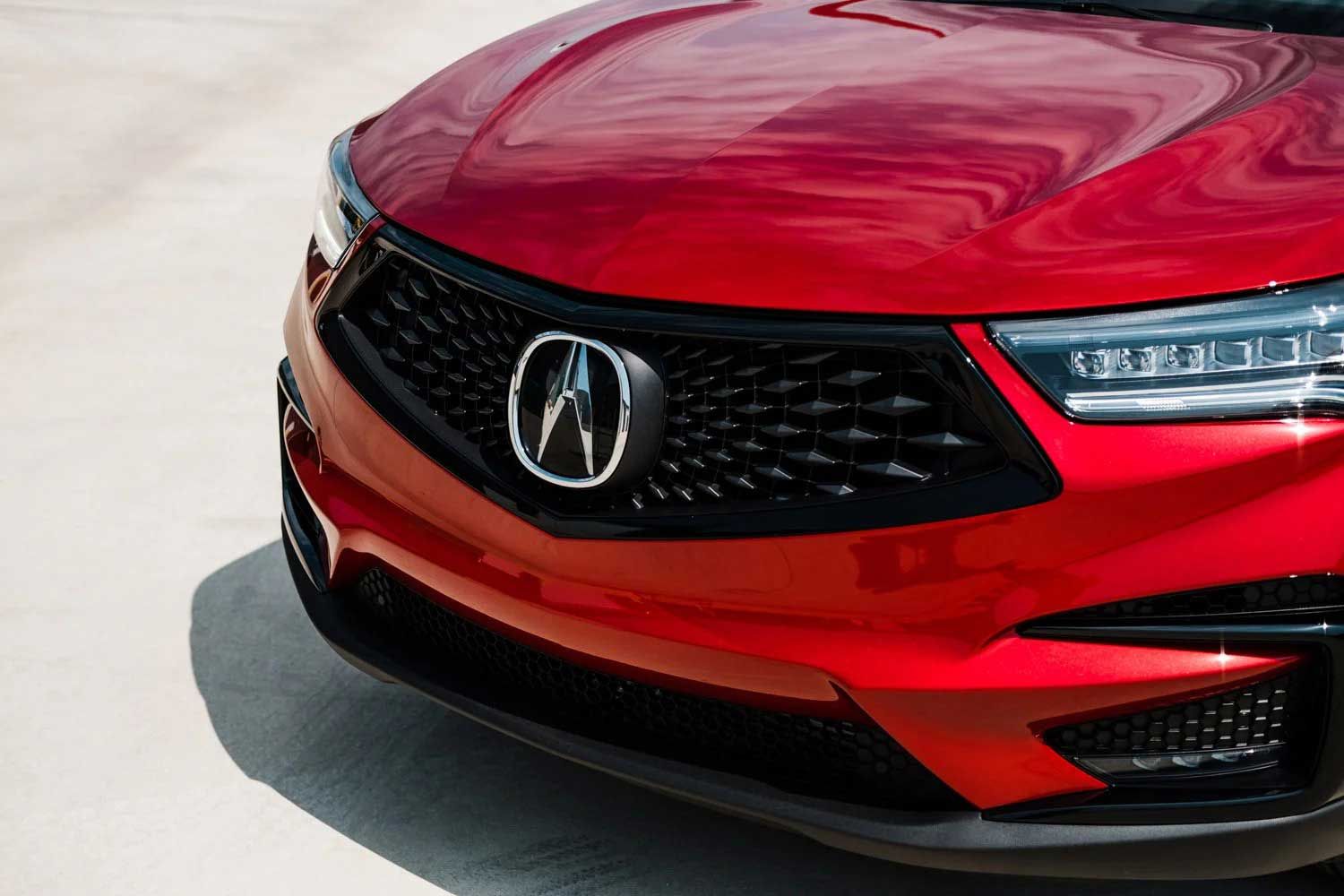 Red Acura RDX front end with black grille and silver emblem.