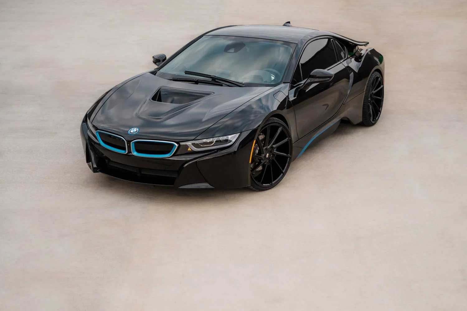 Black BMW i8 sports car on a light-colored surface; blue accents on the front grille and side trim.