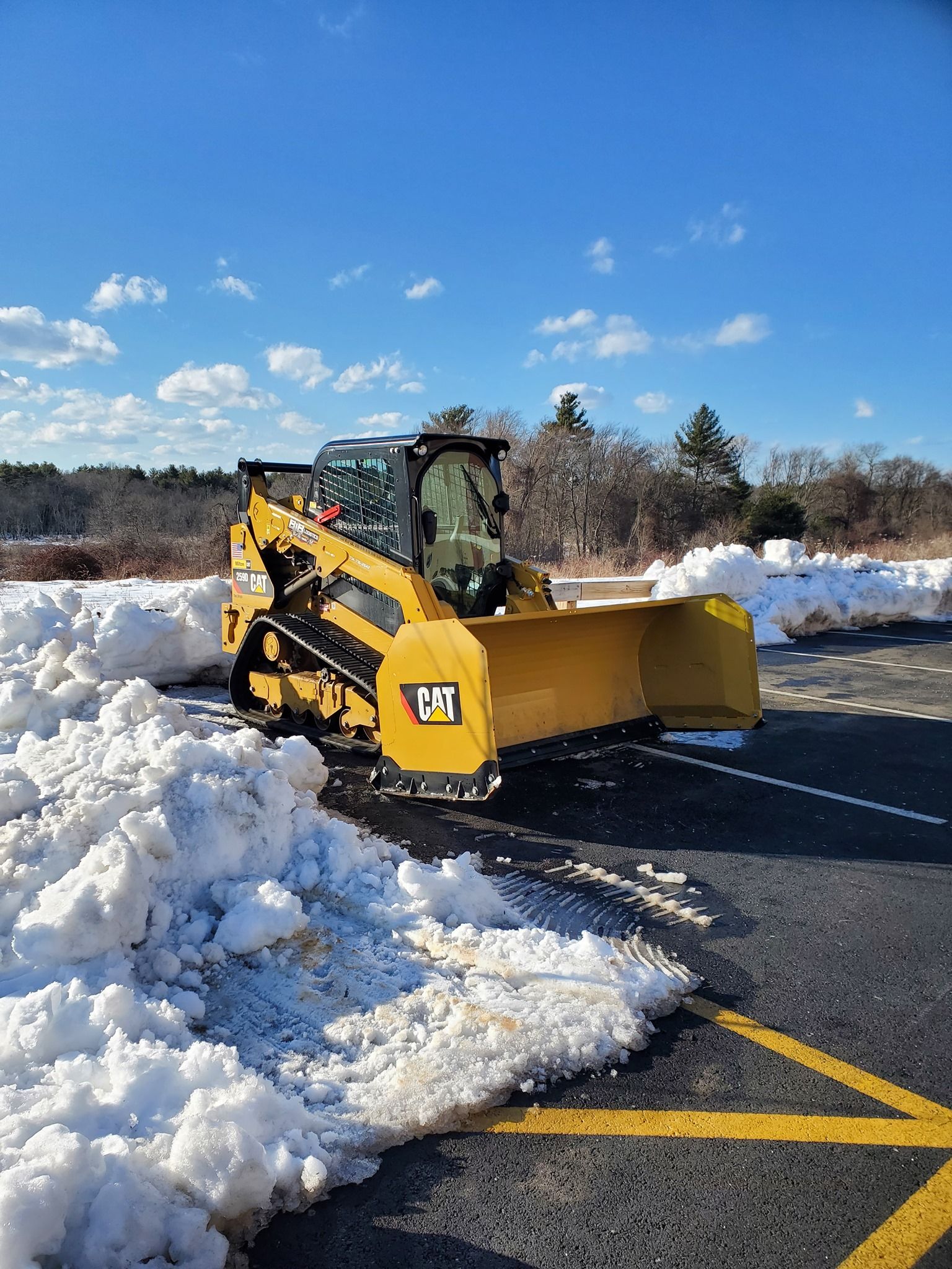 A yellow snow plow is clearing snow from the side of a road.