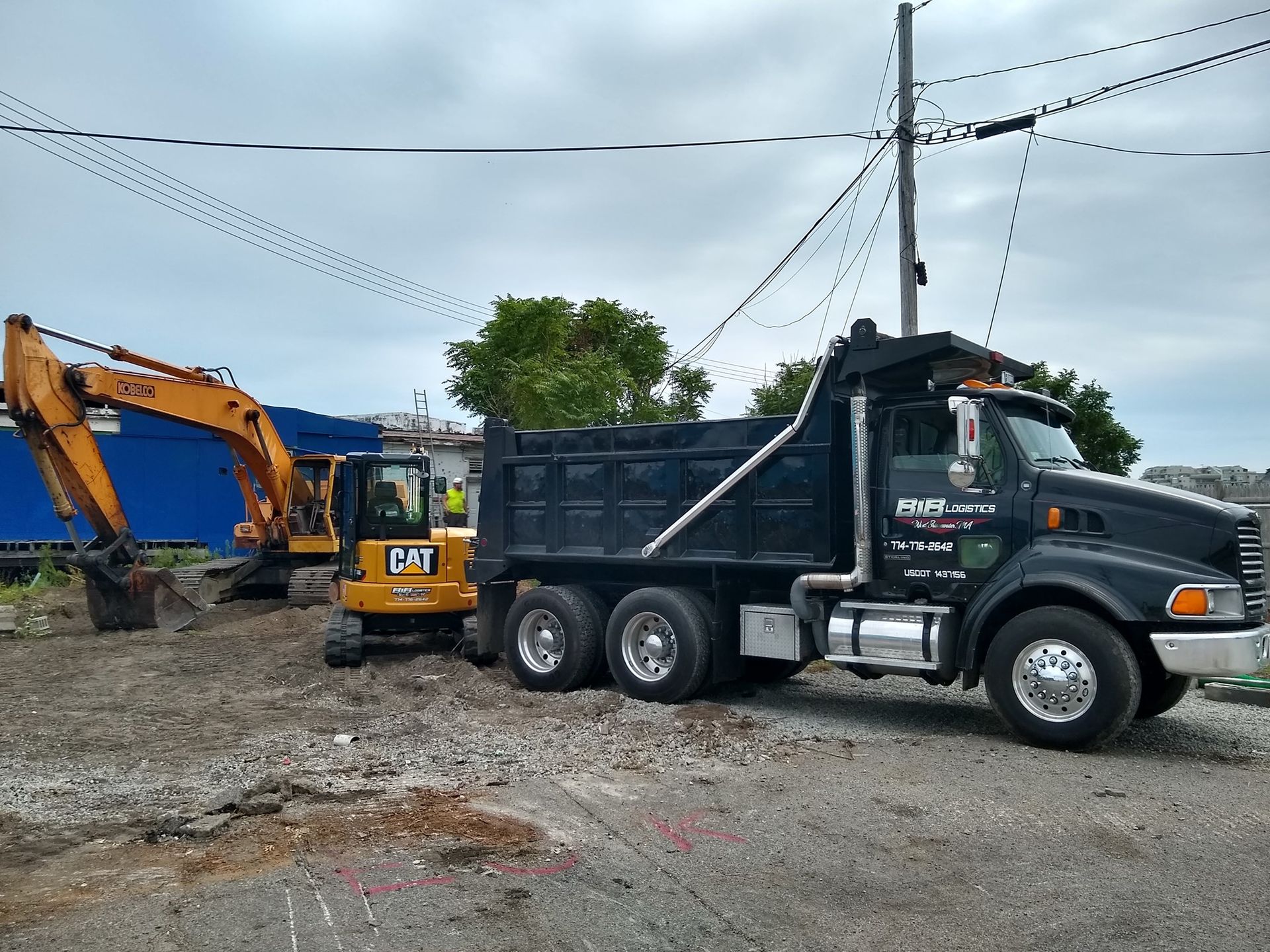 A dump truck and an excavator are parked in a dirt lot.