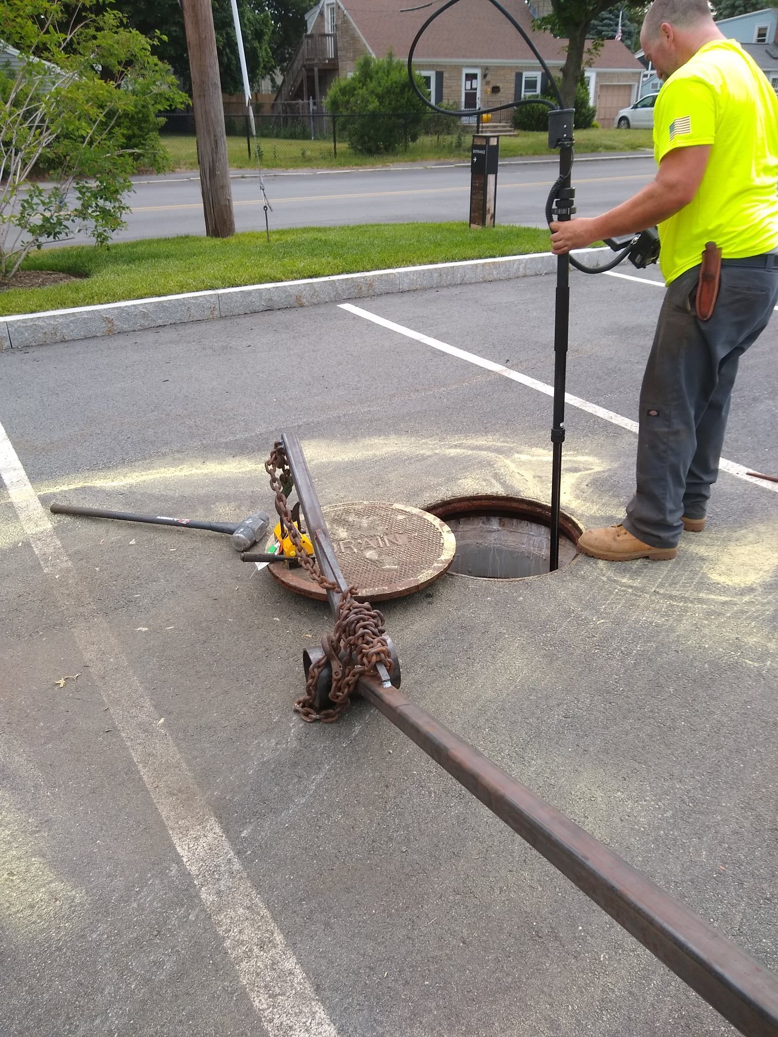 A man is standing next to a manhole cover in a parking lot.
