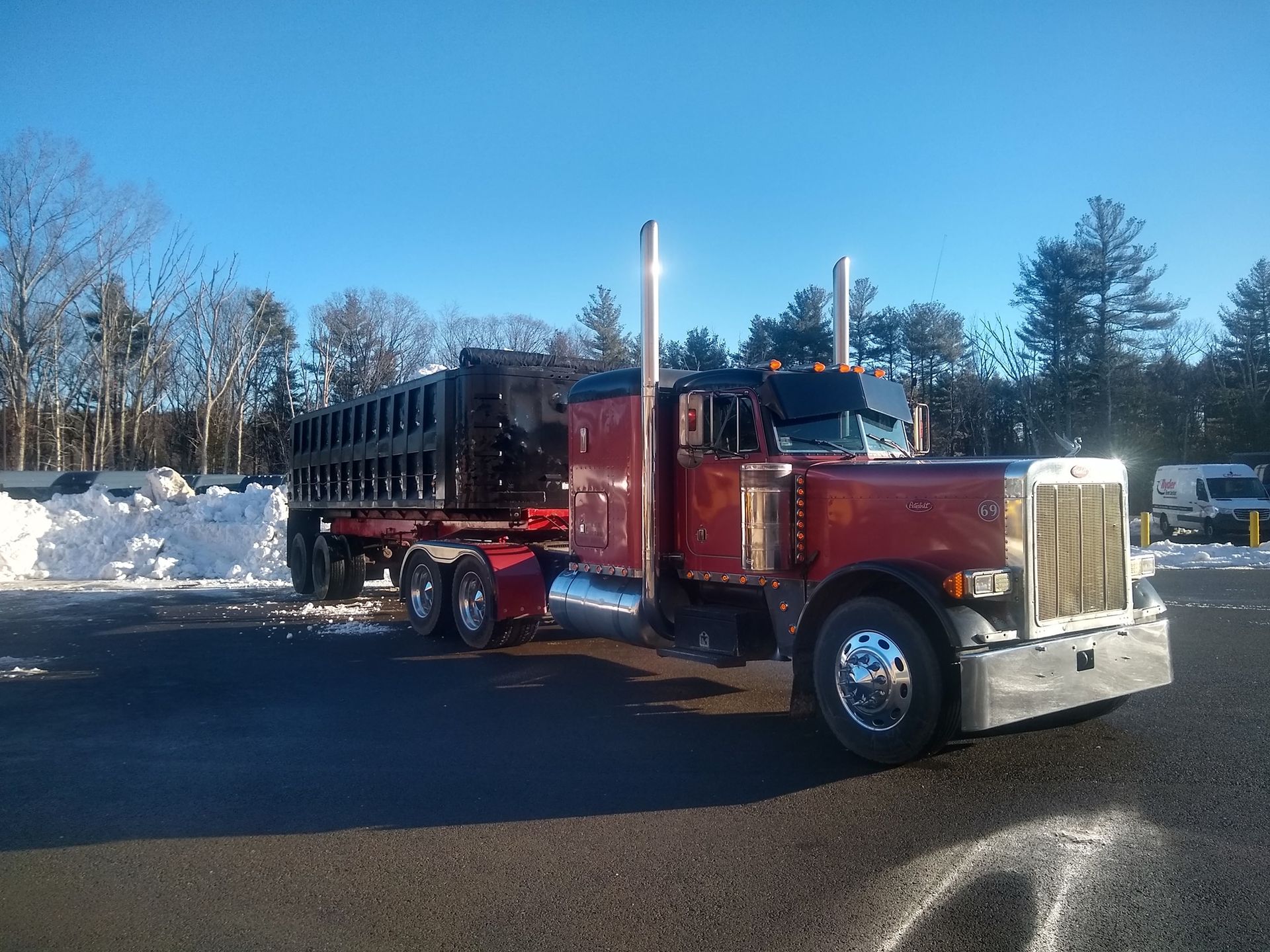 A red semi truck is parked in a snowy parking lot
