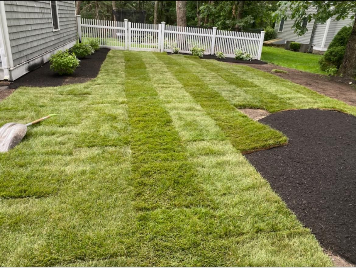 A lush green lawn with a white picket fence in the background.