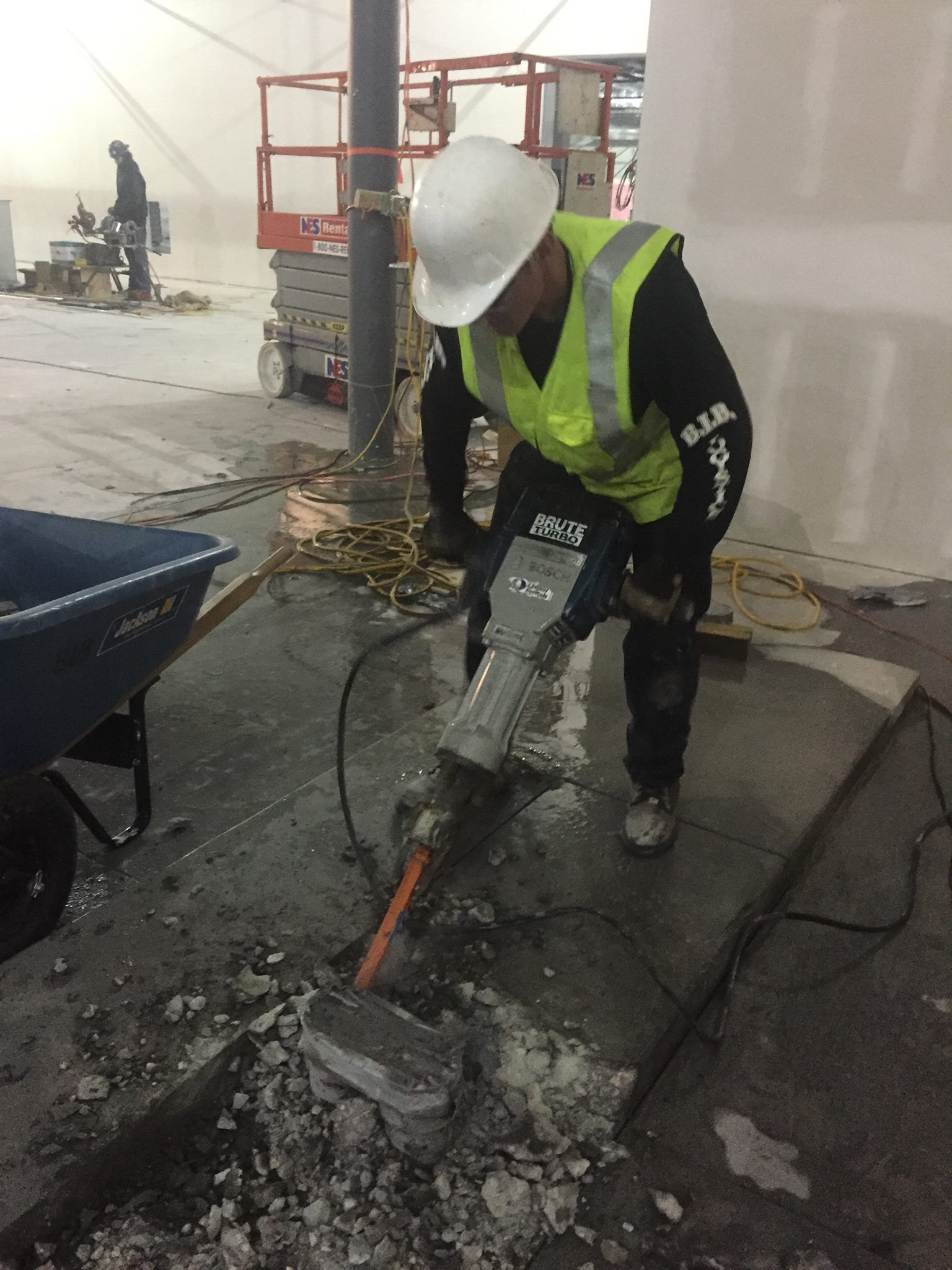 A construction worker is using a hammer to break concrete.