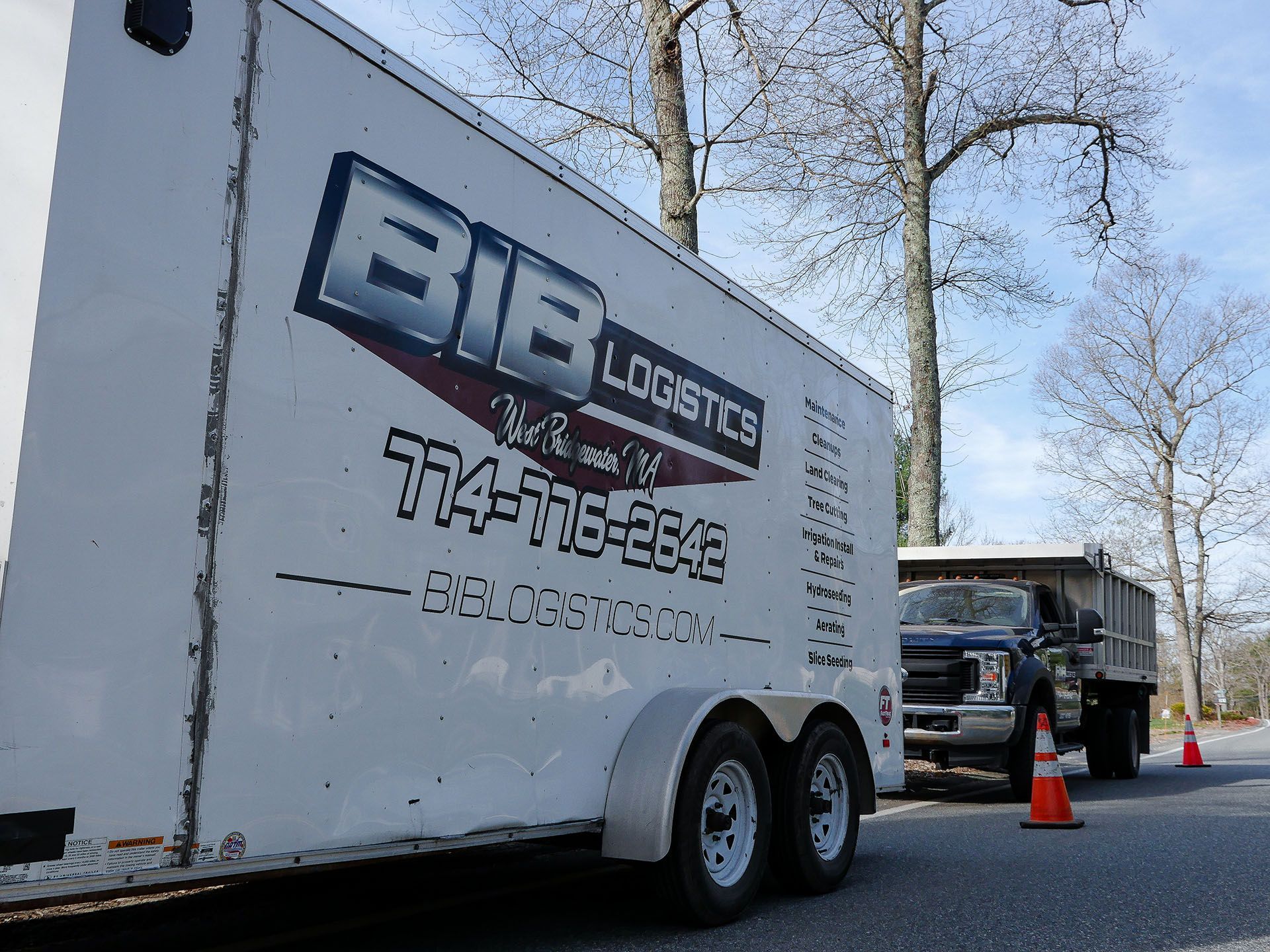 A white bib logistics trailer is parked on the side of the road