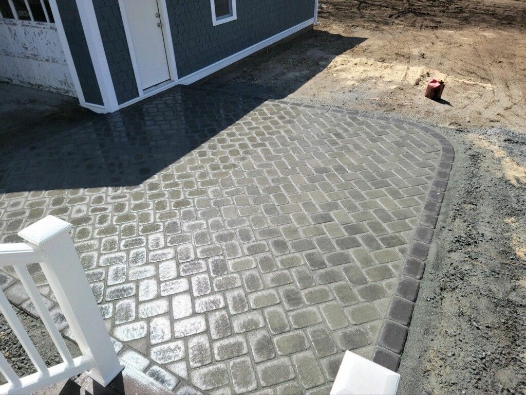 A patio with a white railing and a shed in the background.