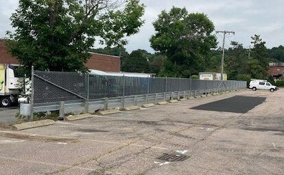A truck is parked in a parking lot next to a chain link fence.