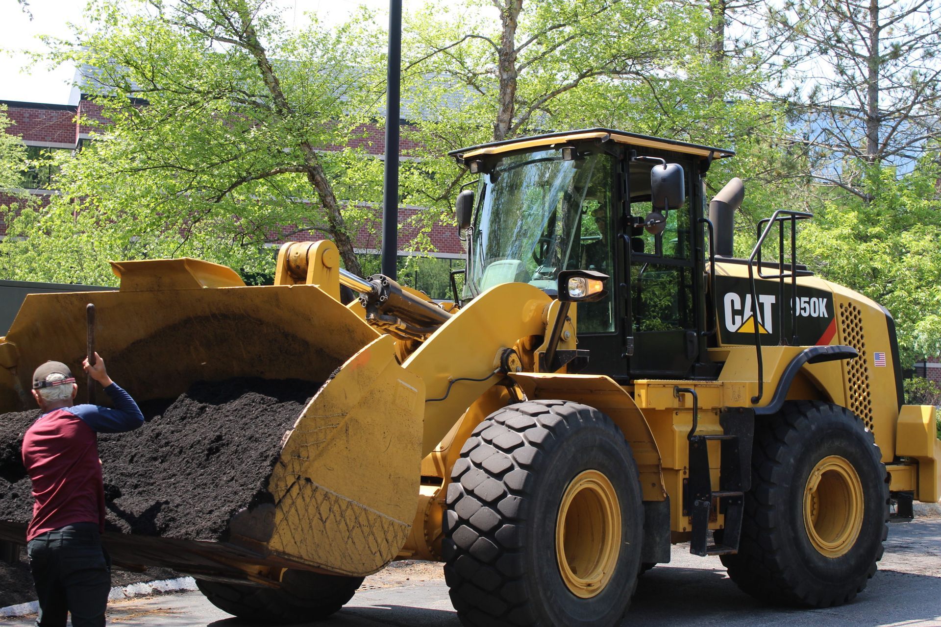 A man is standing next to a yellow cat wheel loader