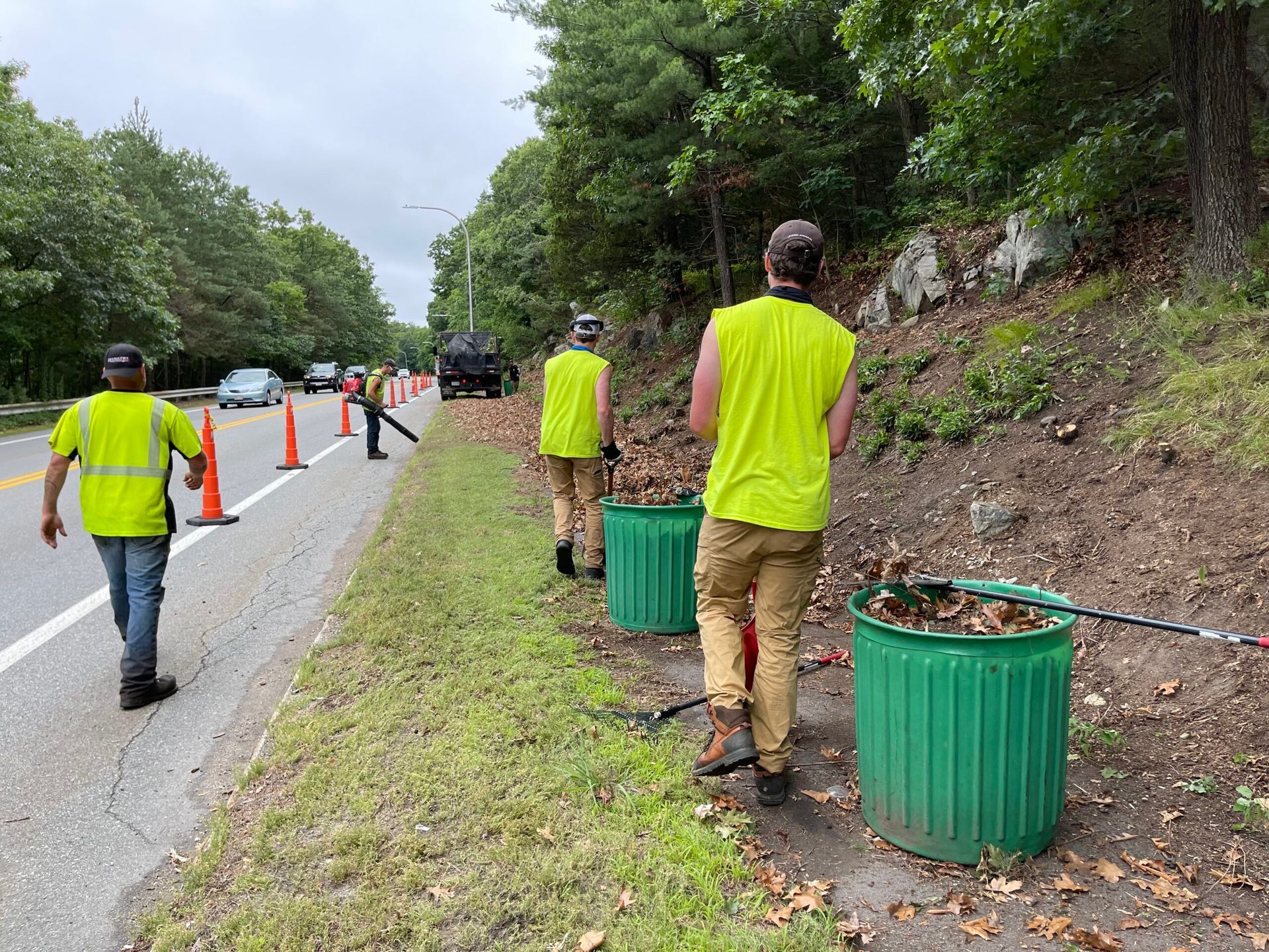 A group of men are walking down a sidewalk next to a road.