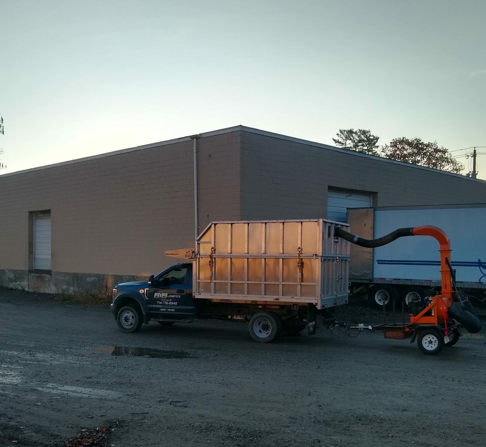 A truck with a trailer attached to it is parked in front of a building