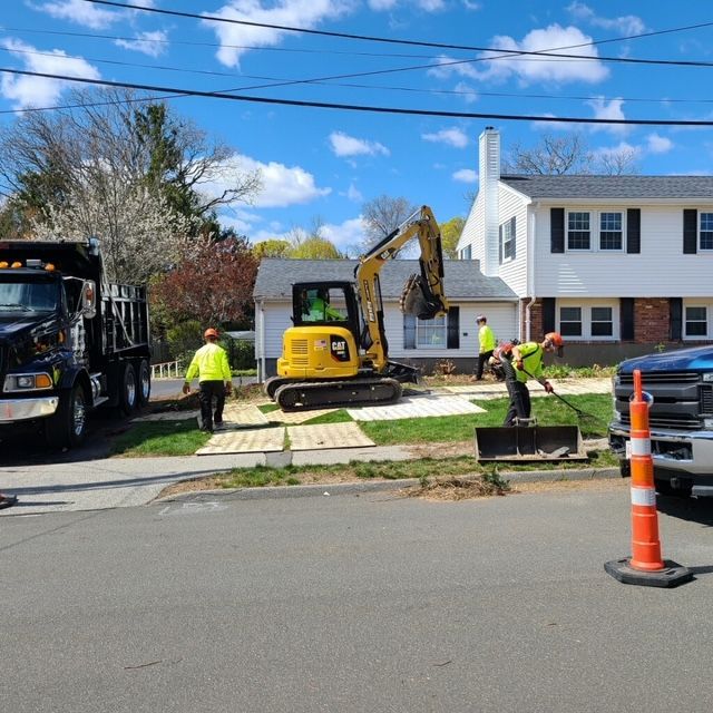 Construction workers are working on a driveway in front of a house