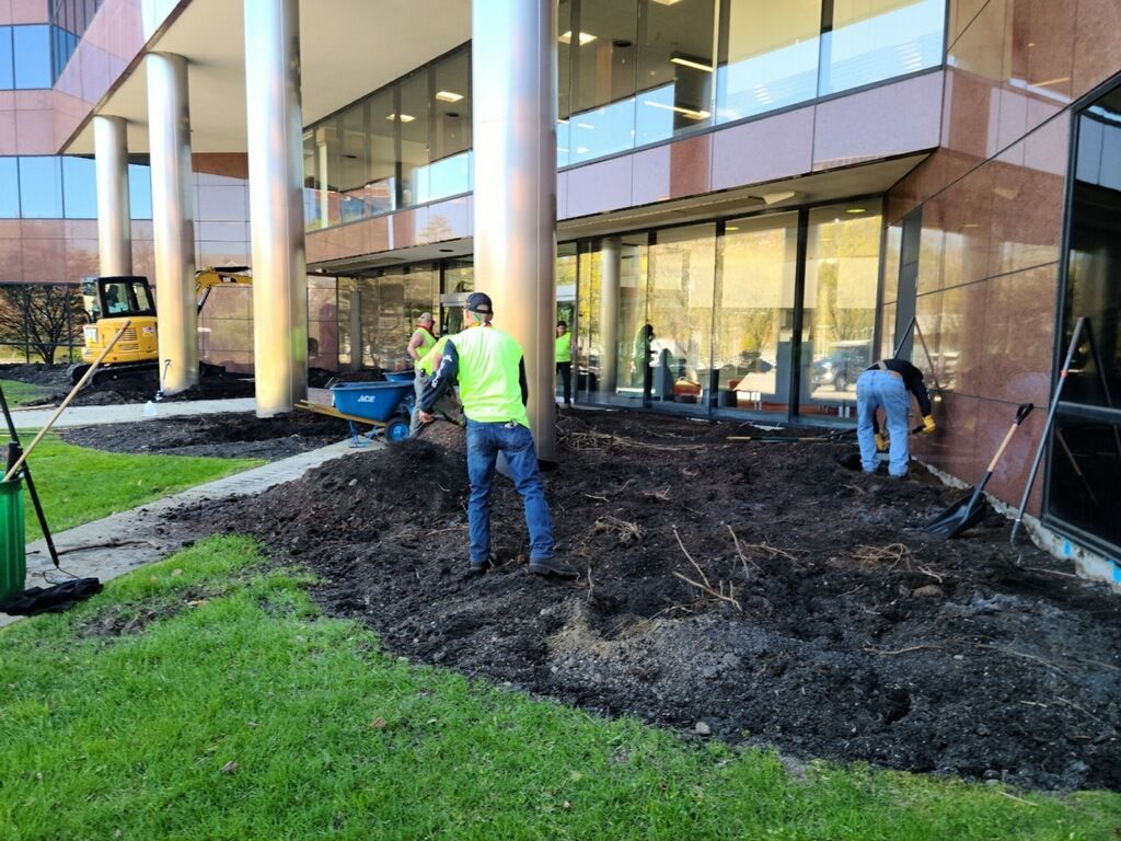 A group of people are digging in the dirt in front of a building.