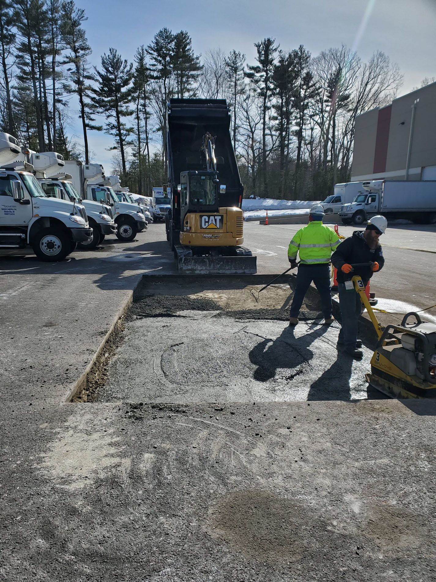 A group of construction workers are working on a parking lot.