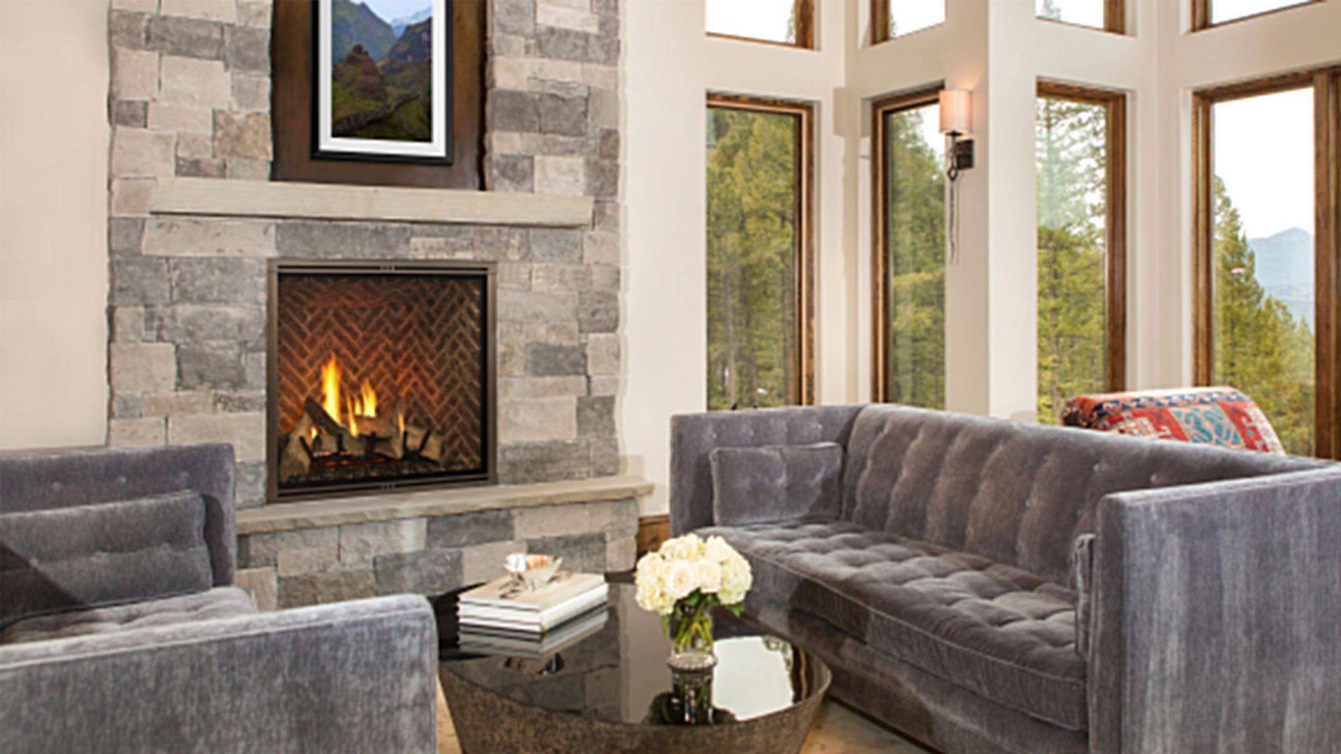 Living room with a stone fireplace, gray sofa, armchair, and coffee table.