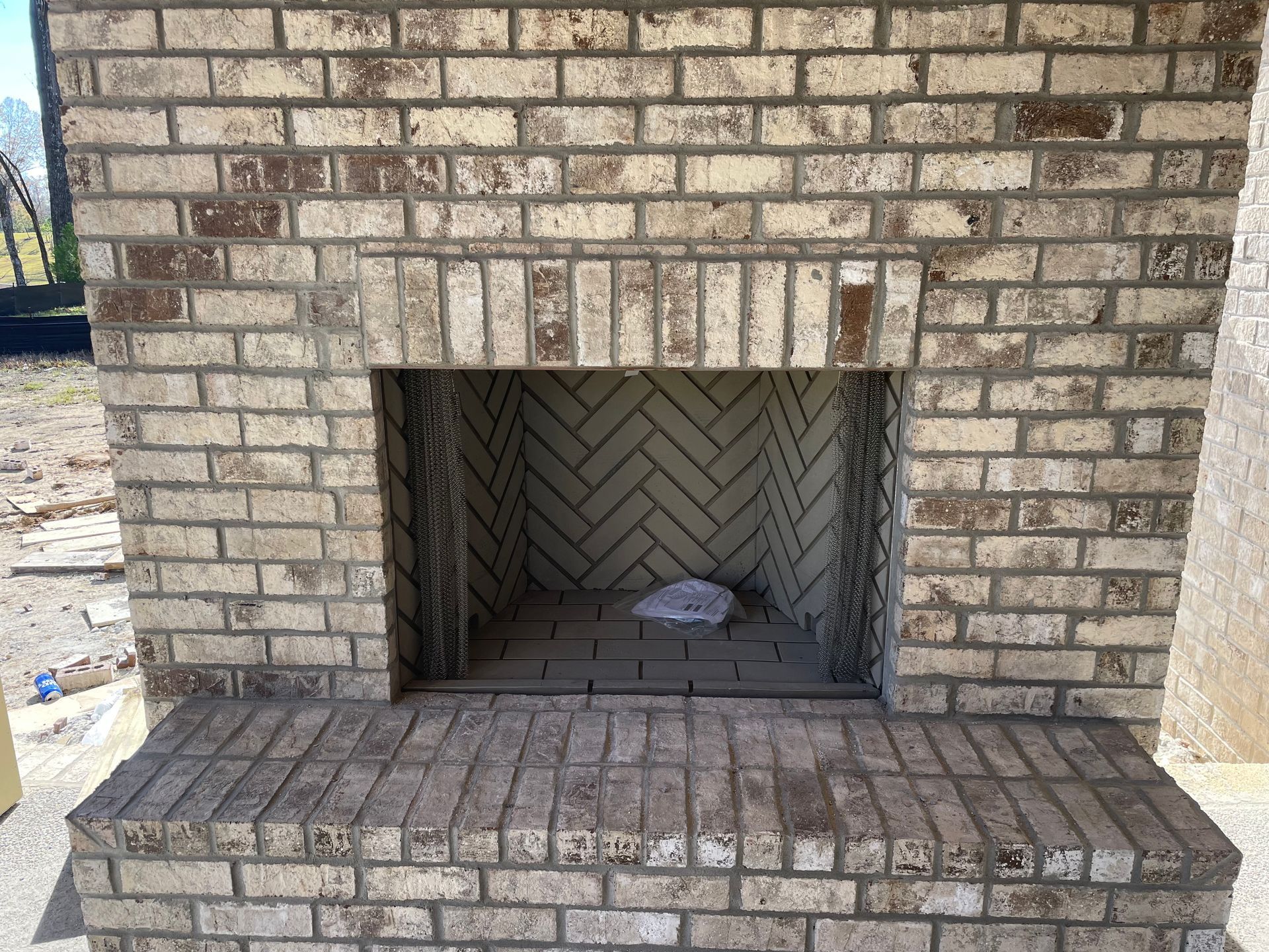 A brick fireplace with a herringbone pattern on the wall.