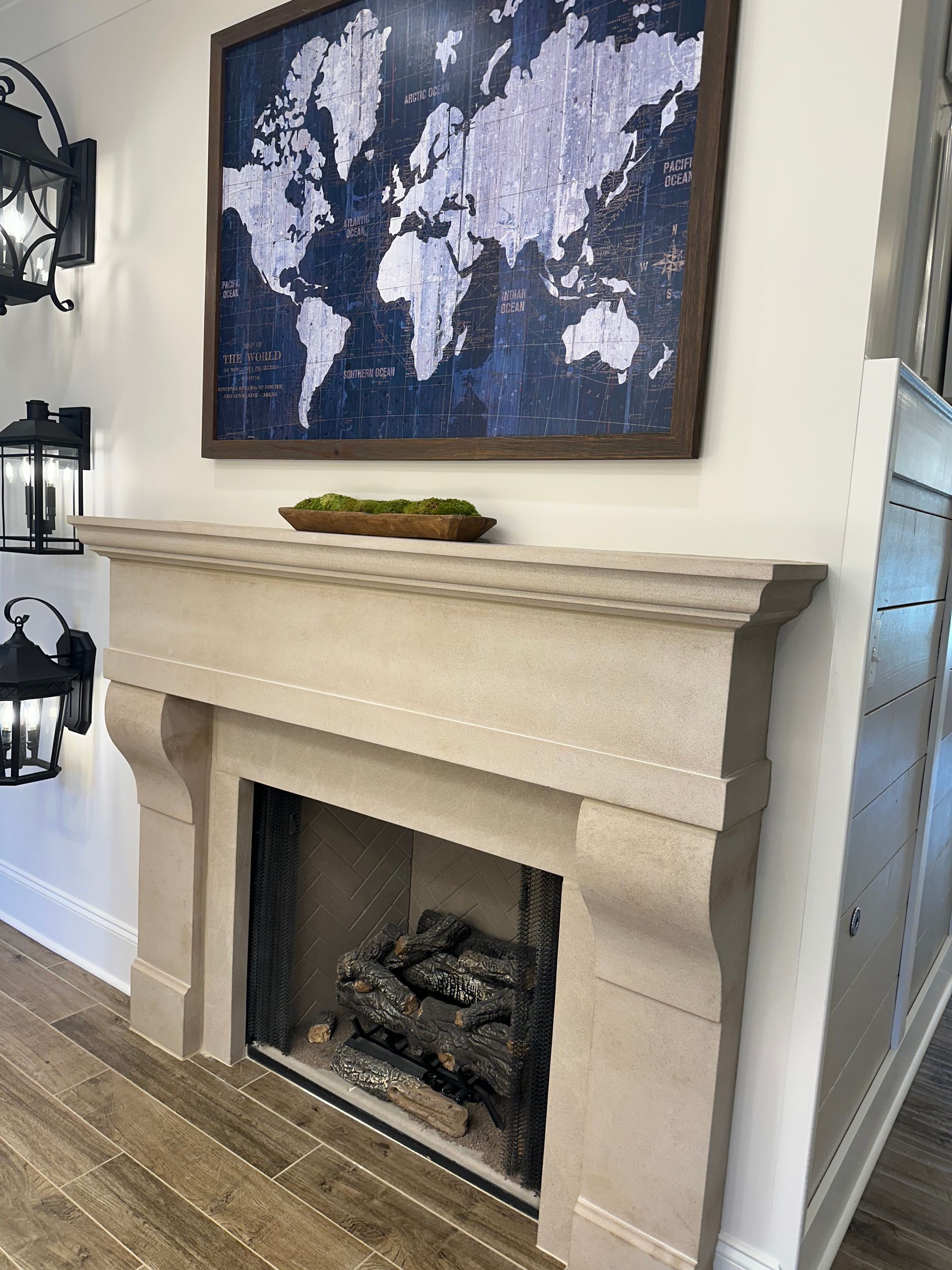 Fireplace with a map art, moss bowl, and wall sconces.