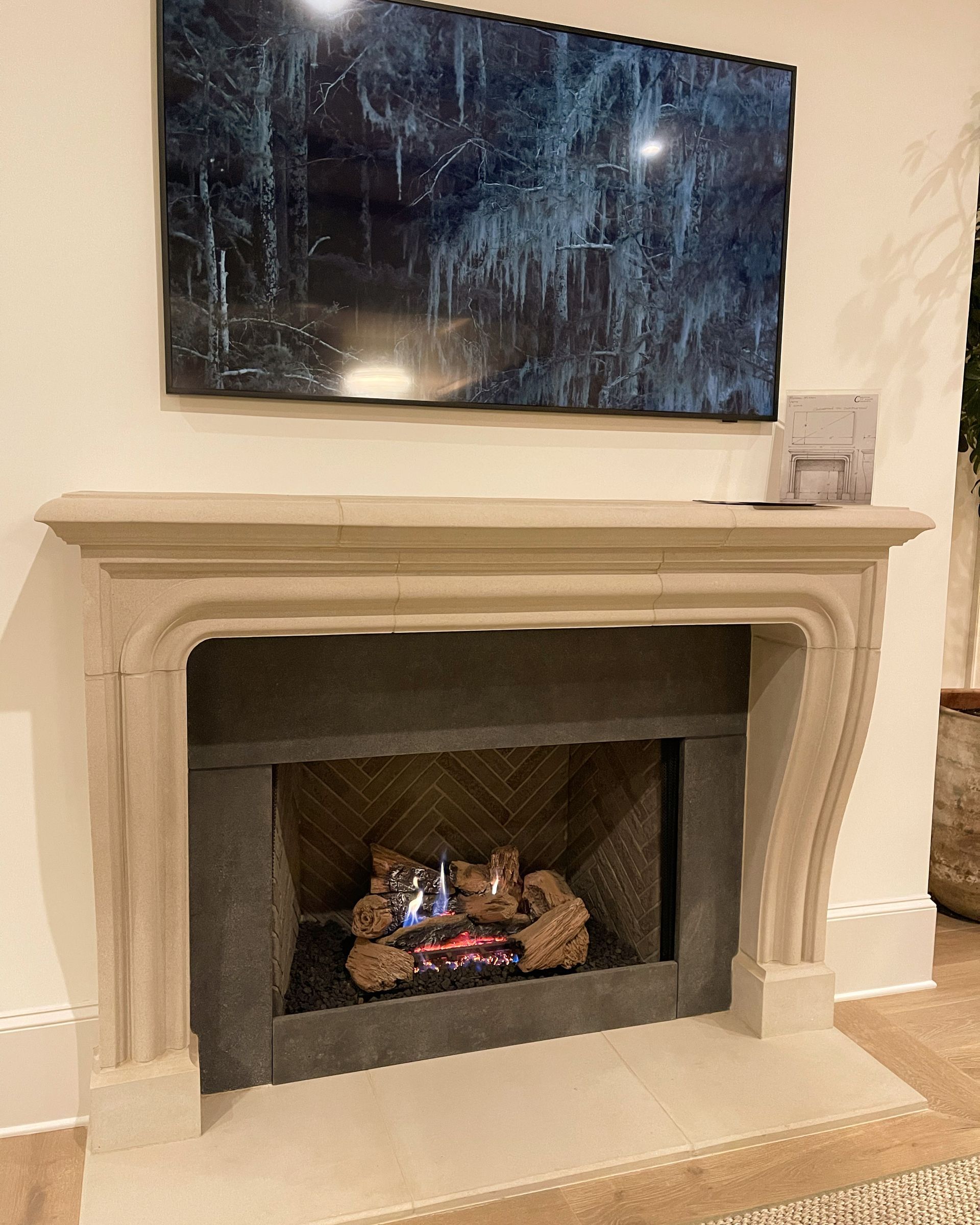 Fireplace with stone mantel, gas fire, TV above displaying icicles, on a cream-colored wall.