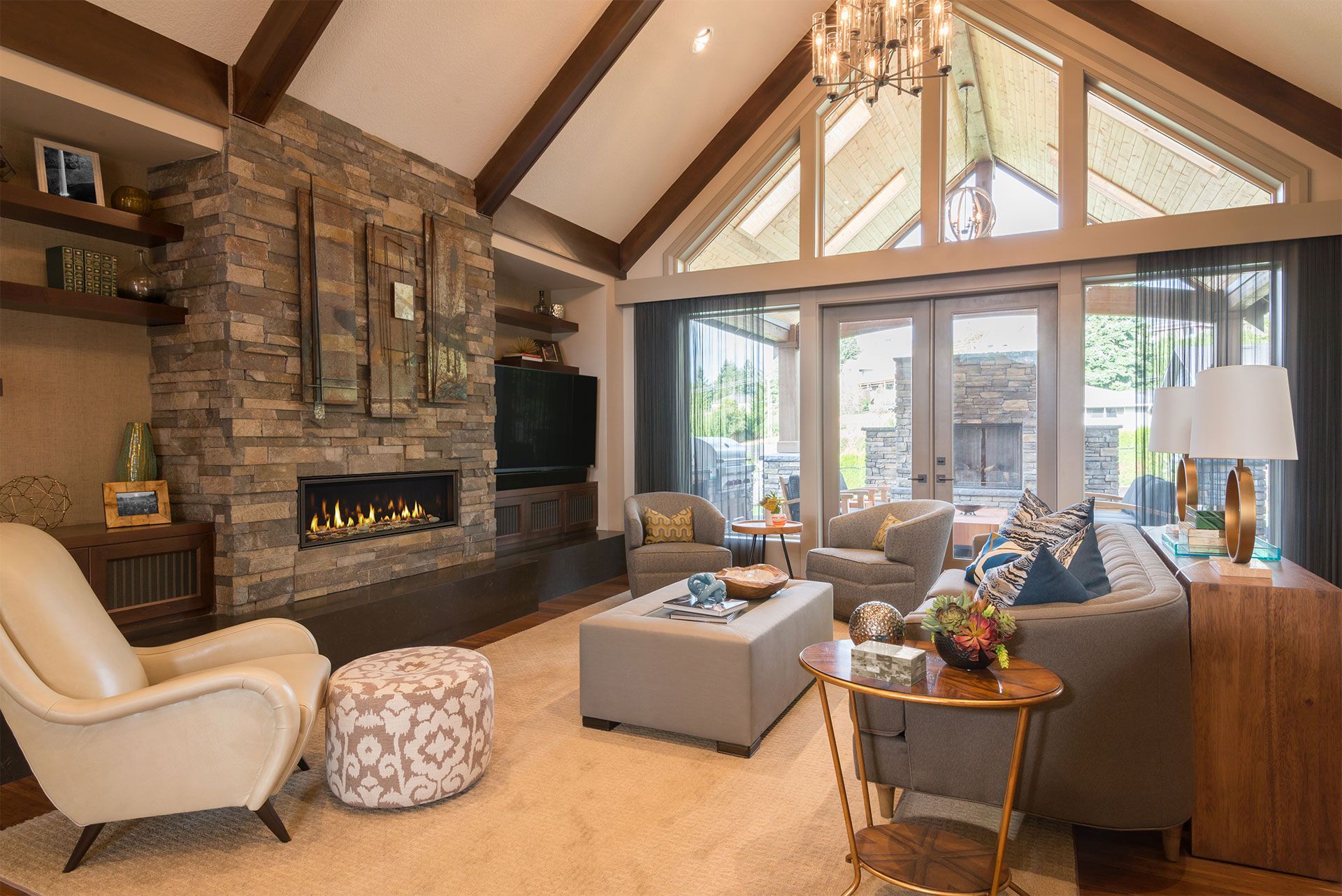 Living room with stone fireplace, vaulted ceiling, and outdoor patio access.