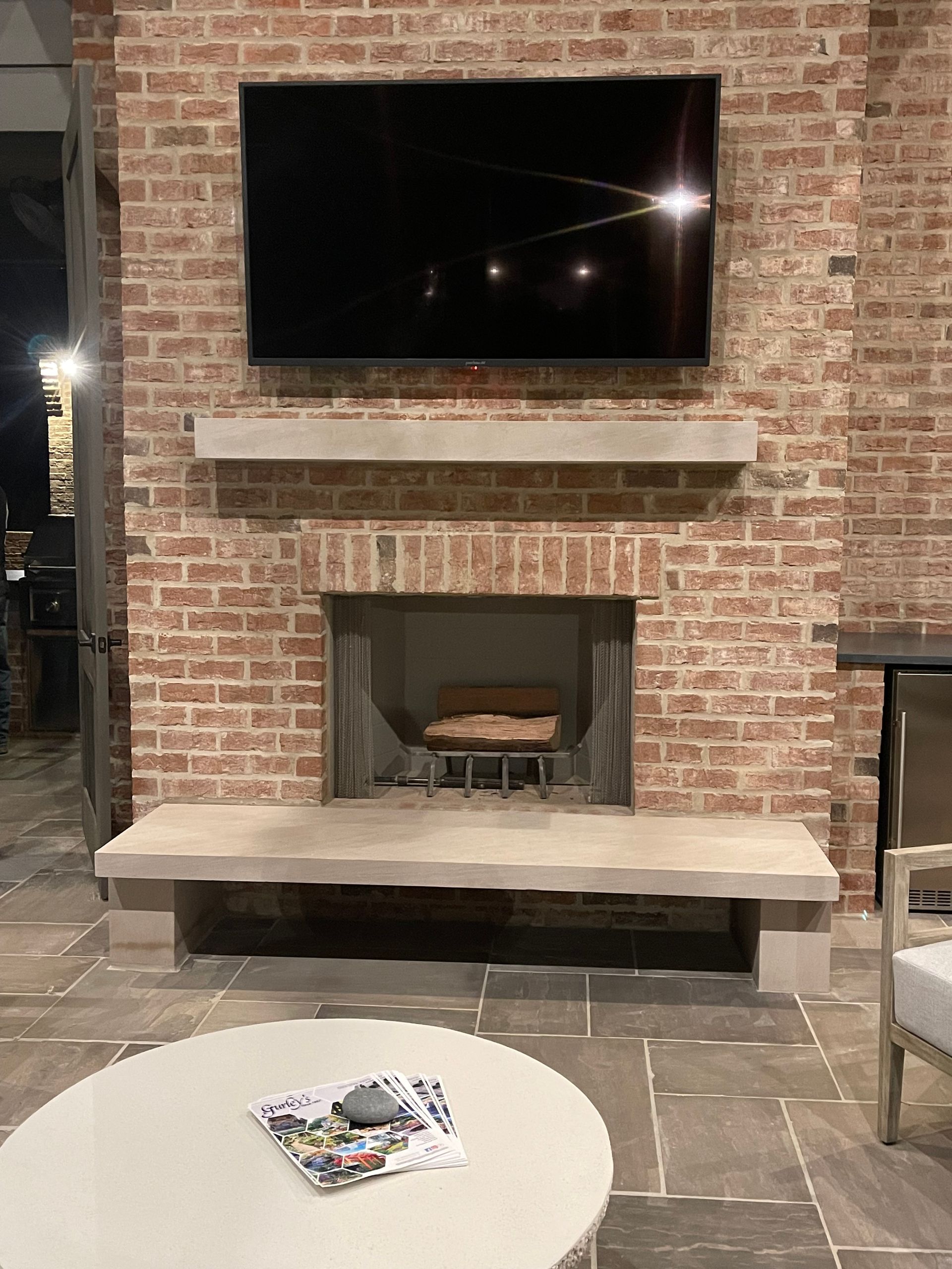 Brick fireplace with a mounted TV and concrete mantel and hearth.