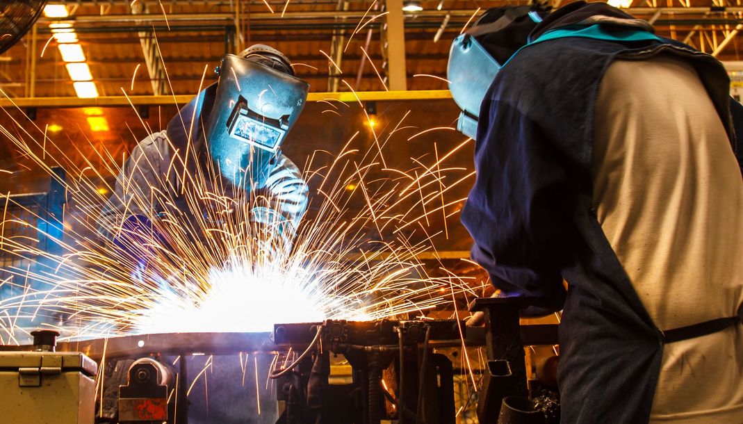 Welders in protective gear creating bright sparks in an industrial workshop