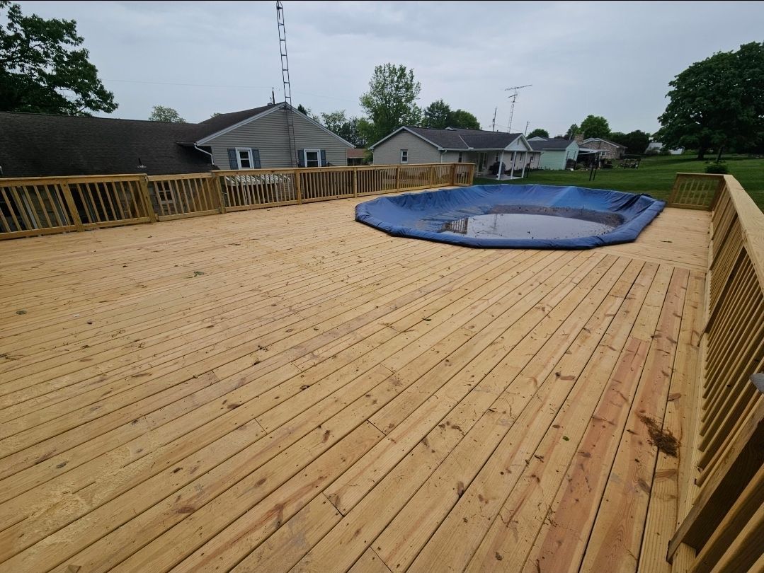Wooden deck with a blue pool cover, houses in the background.