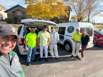 A group of employees are posing for a picture in front of a van.