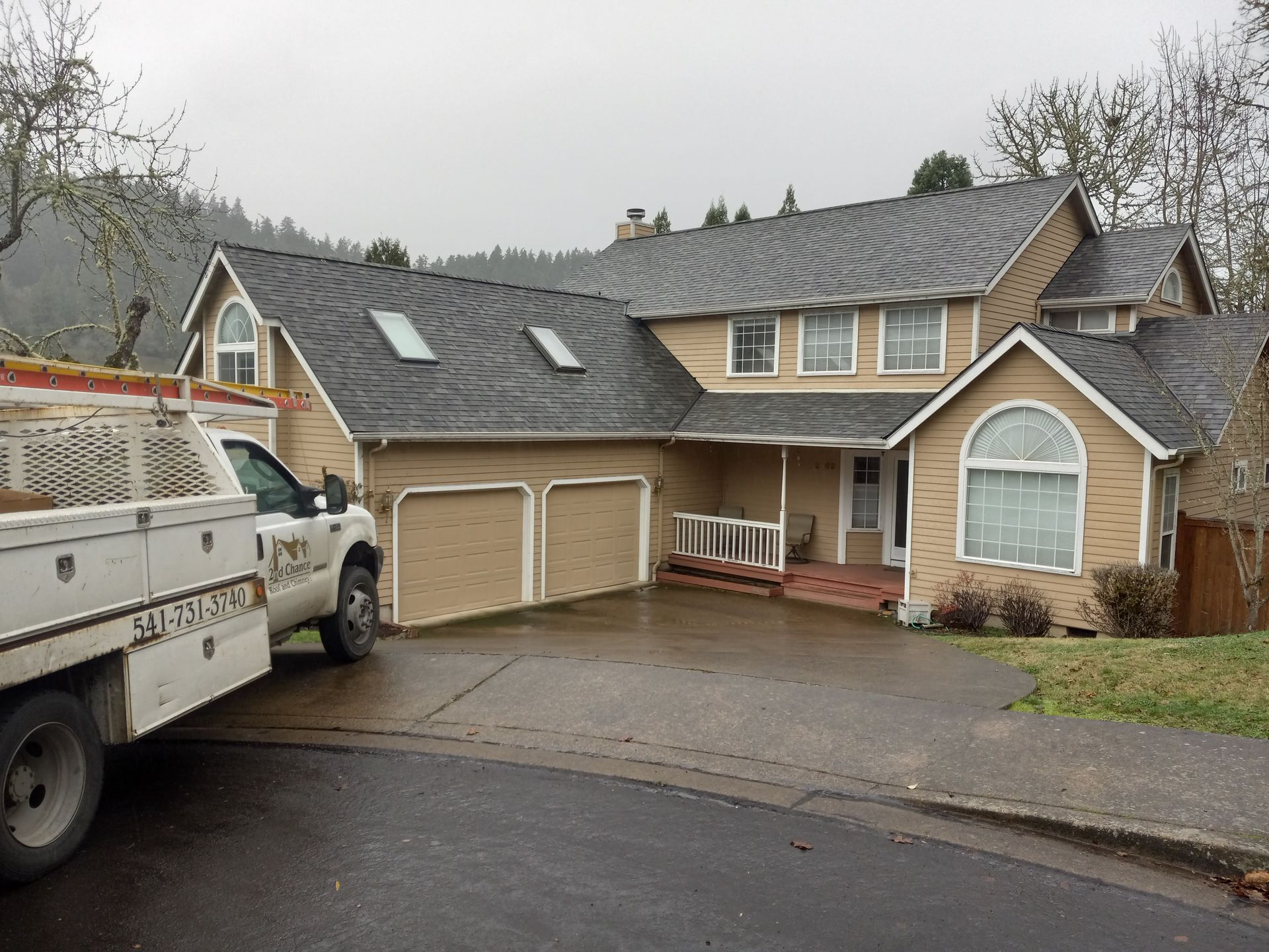 Tan house with dark roof and two-car garage; work truck parked in front.