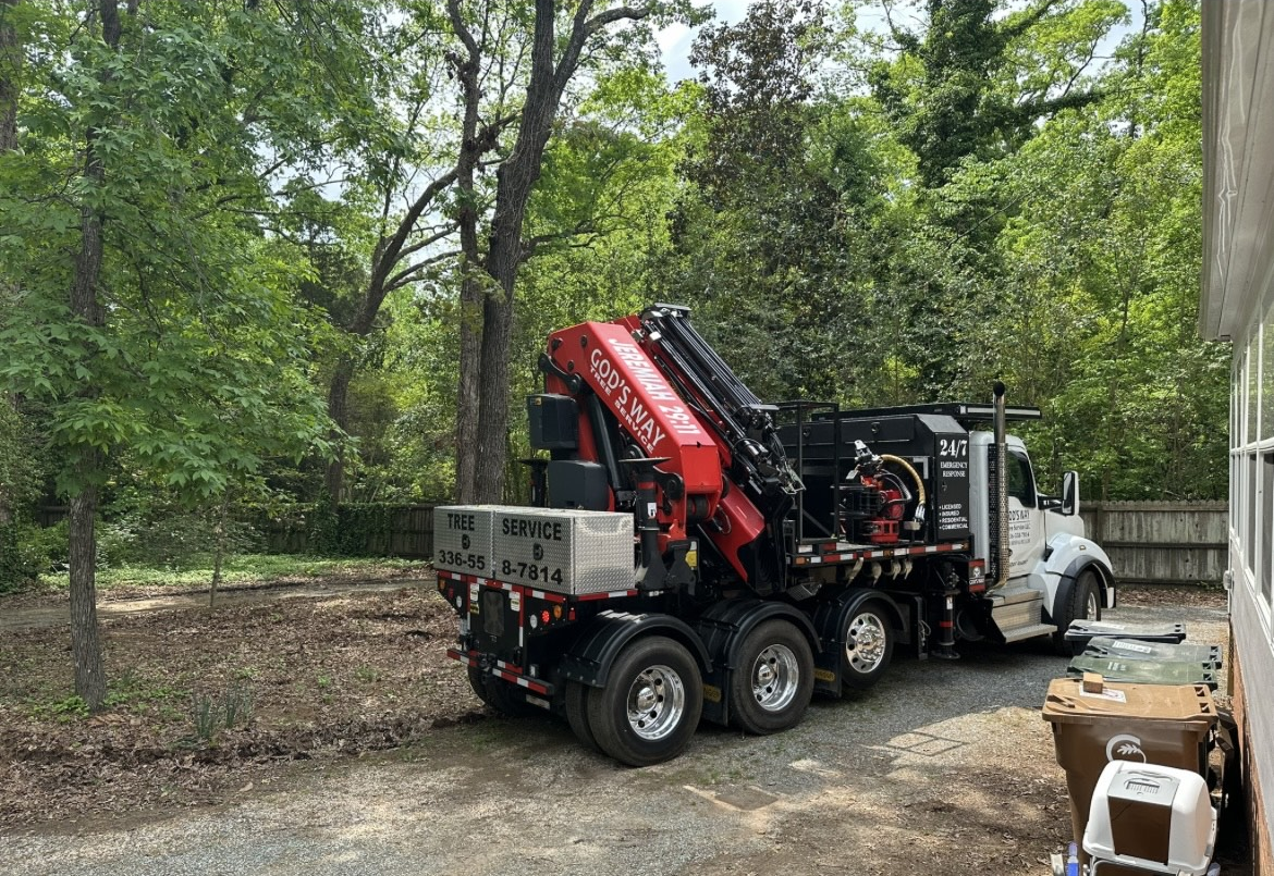 A large truck with a crane on the back is parked in a driveway.