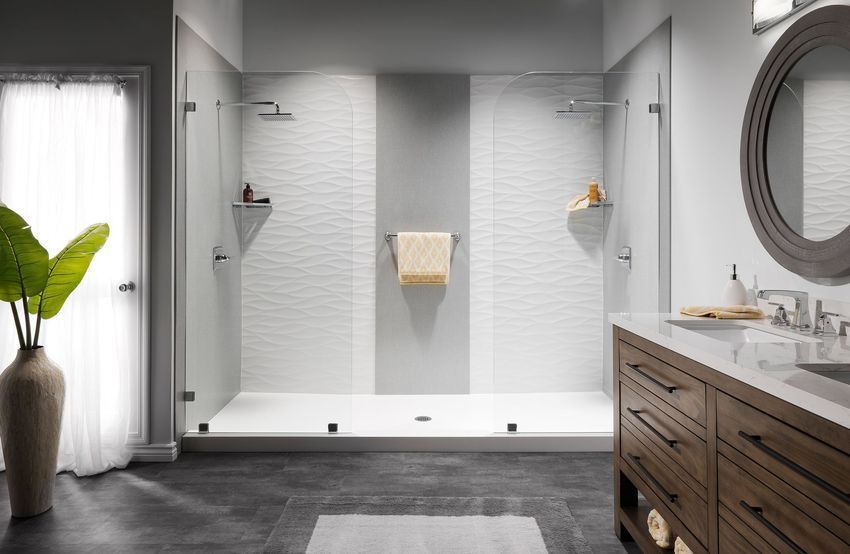 Modern bathroom with a large shower, white textured tile walls, and gray accent, with a vanity and large round mirror.