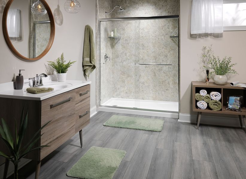 Bathroom with wood vanity, glass shower, gray floor, green rugs, and beige walls.