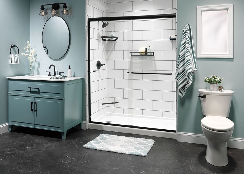 Bathroom with blue walls, black accents, white shower, and vanity, with dark flooring.