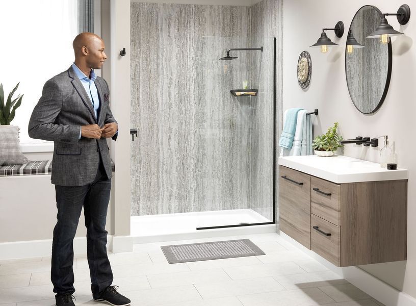 Man in suit adjusting jacket in modern bathroom with shower.