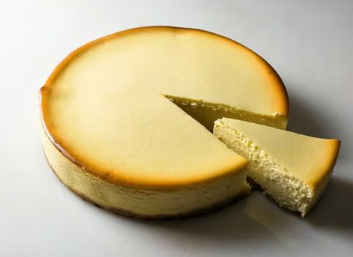 Round cheesecake with a slice cut out on a white background