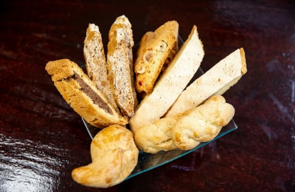 Assorted bread rolls and sliced loaves arranged in a fan on a dark table