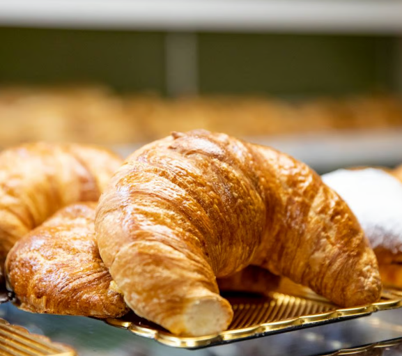 Golden-brown croissants on a bakery tray, fresh and flaky