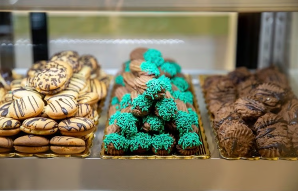 Three trays of assorted cookies and pastries, including chocolate, turquoise-topped, and iced varieties.