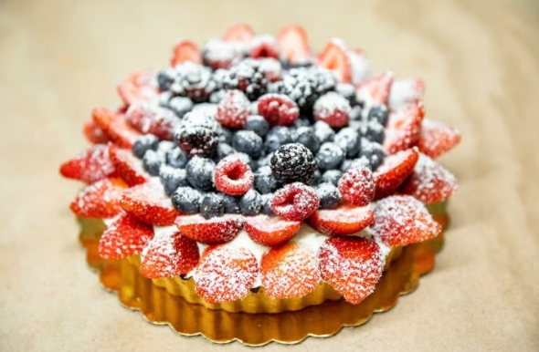 Powdered berry tart with raspberries and blueberries in a golden crust