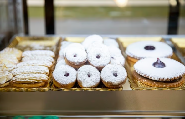 Tray of powdered sugar doughnuts in a bakery display case