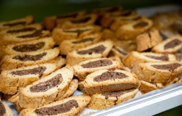 Tray of sliced rolled pastries filled with dark filling, arranged in rows