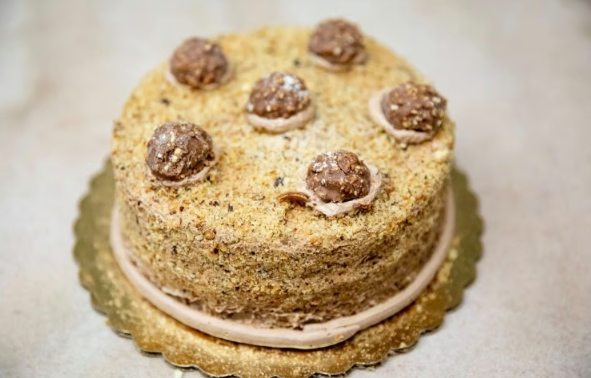 Round layered cake with chocolate truffles on top and cream filling on a gold cake board