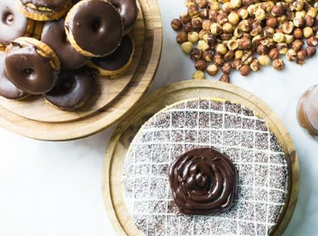 Chocolate-covered donuts on wooden boards with a powdered pastry topped with chocolate spread.